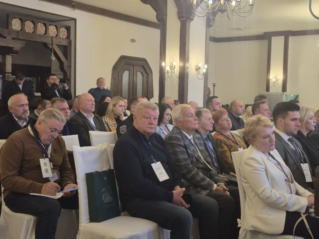 Група людей на конференції в залі з люстрами.