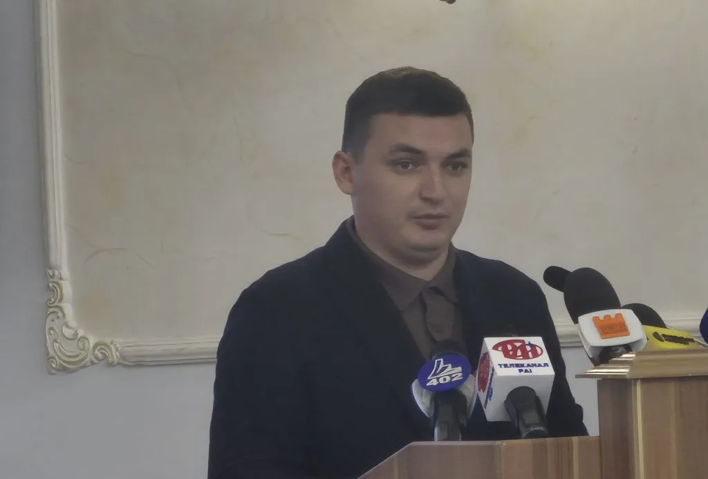 Чоловік виступає на пресконференції за трибуною