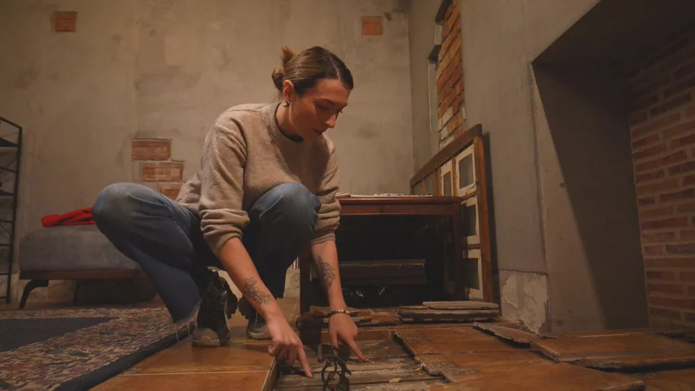Жінка ремонтує дерев’яну підлогу у старій кімнаті