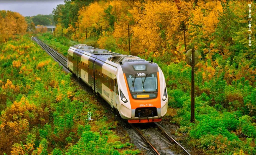 Сучасний потяг Укрзалізниці серед осіннього лісу