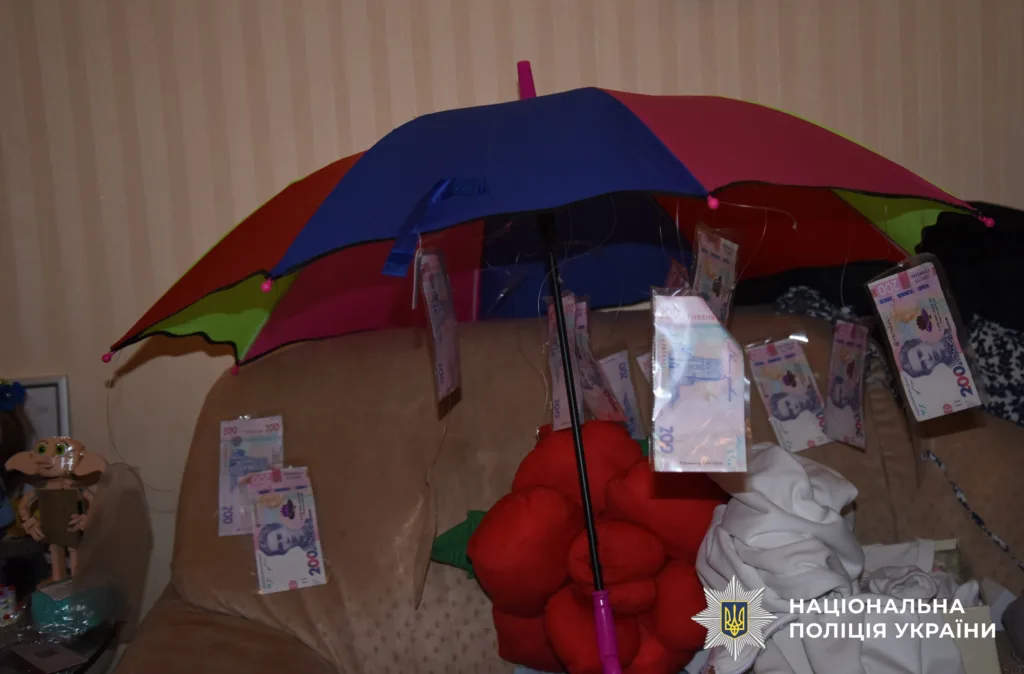 Кольоровий парасоль з підвішеними гривнями на дивані