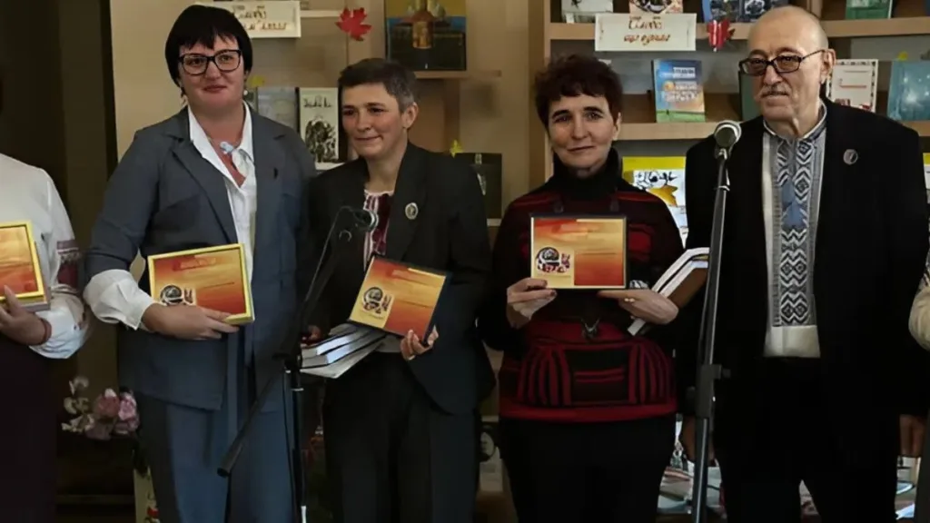 Група людей тримає нагороди у бібліотеці