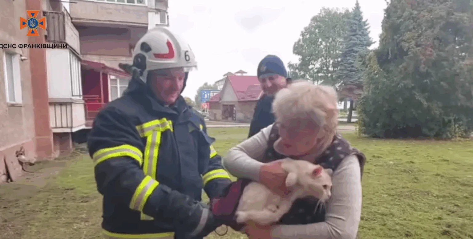 Рятувальник передає жінці врятованого кота