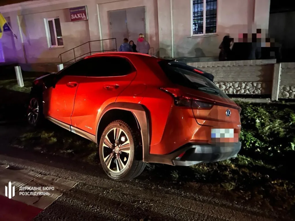 Червоний автомобіль Lexus біля будівлі вночі