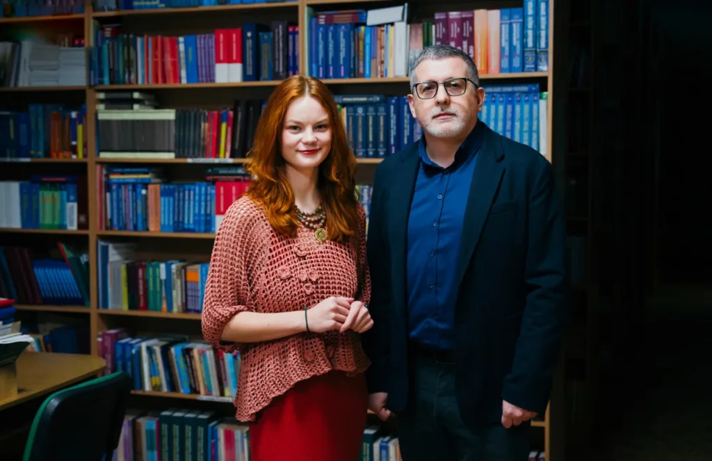 Двоє людей стоять у бібліотеці перед книжками