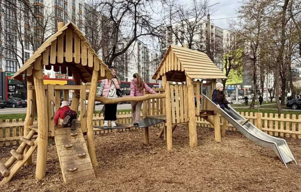 Діти граються на деревому дитячому майданчику