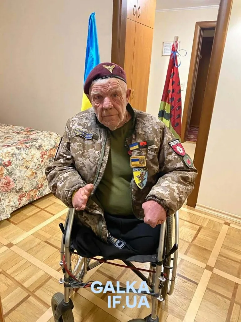 Ветеран у формі сидить у візку з прапорами