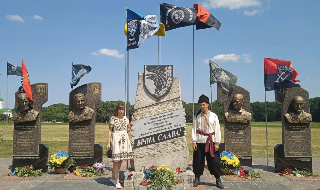 Пам'ятник героям з українськими прапорами та людьми