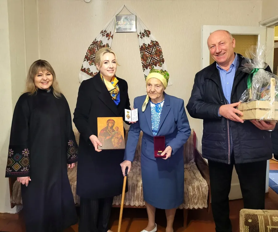 Привітання літньої жінки з подарунками вдома