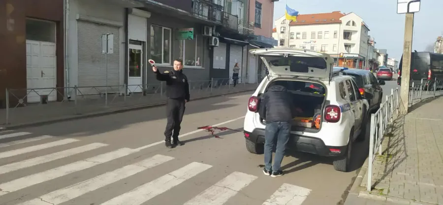 Поліцейський регулює рух біля білого автомобіля