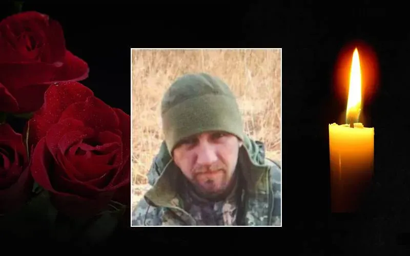 Портрет чоловіка, свічка пам’яті та червоні троянди