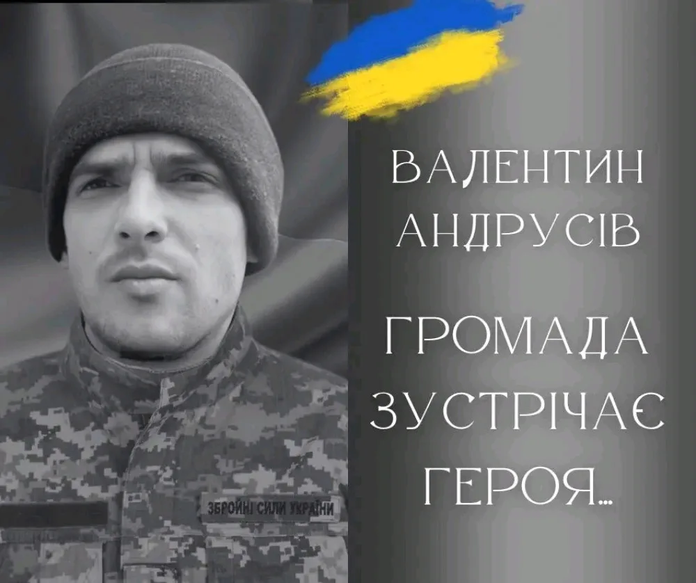 Український військовий у формі перед прапором України