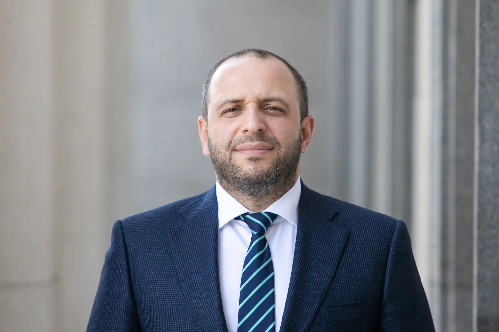 Чоловік у діловому костюмі перед будівлею