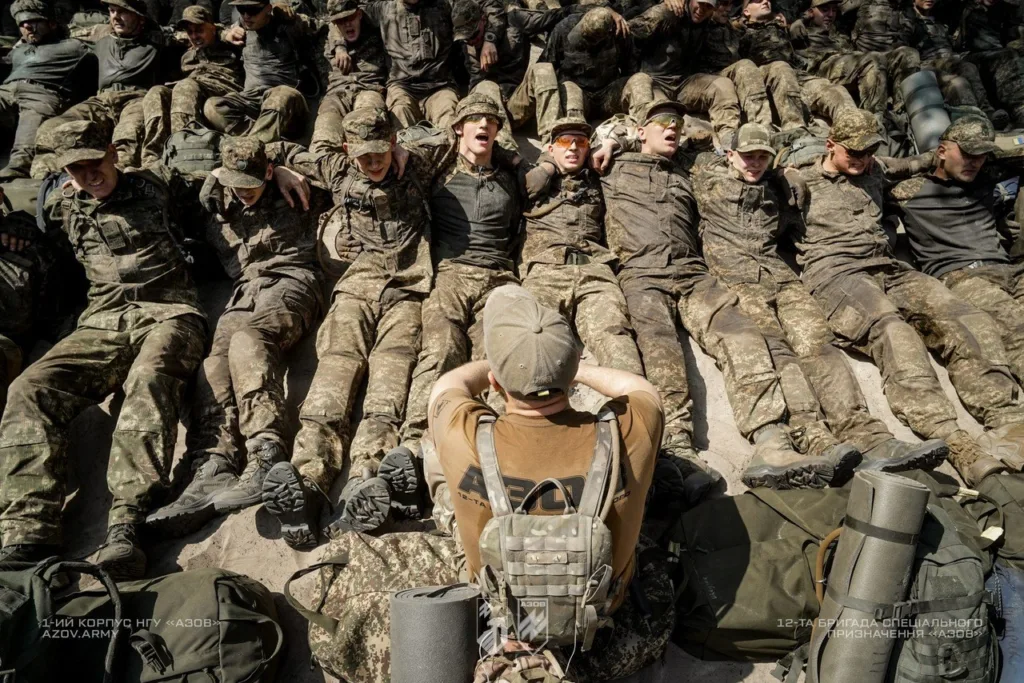 Військові у формі сидять разом на землі