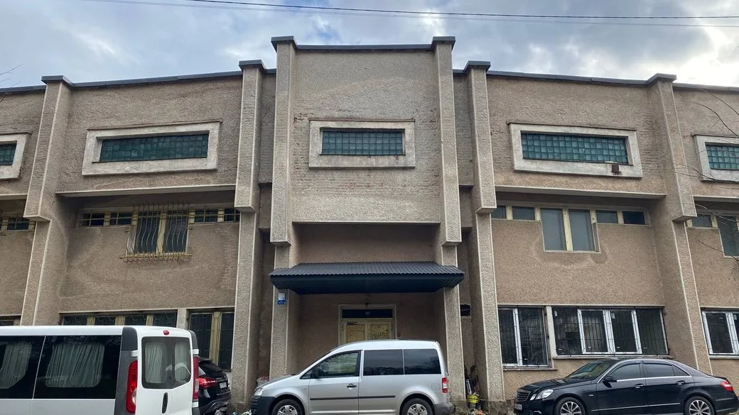 Фасад сірої будівлі з припаркованими автомобілями