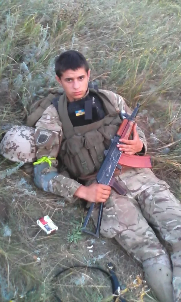 Український військовий відпочиває з автоматом у полі