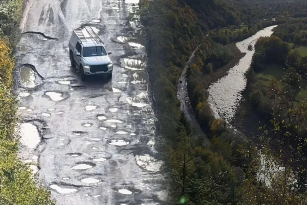 Автомобіль їде розбитою дорогою біля річки