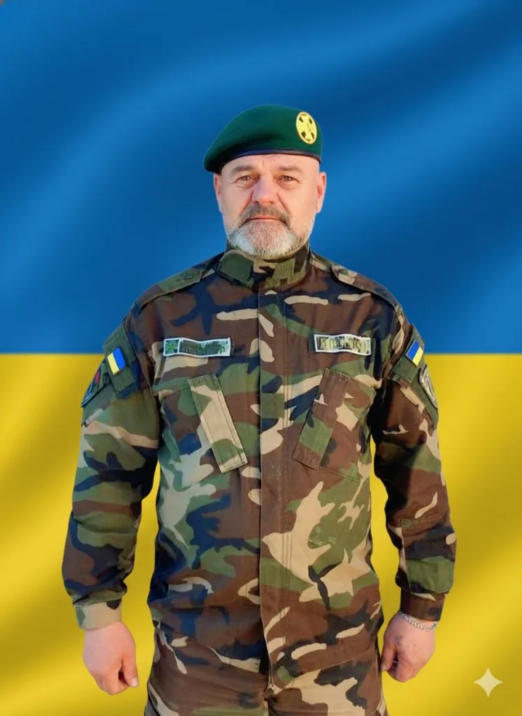 Військовий у формі перед прапором України