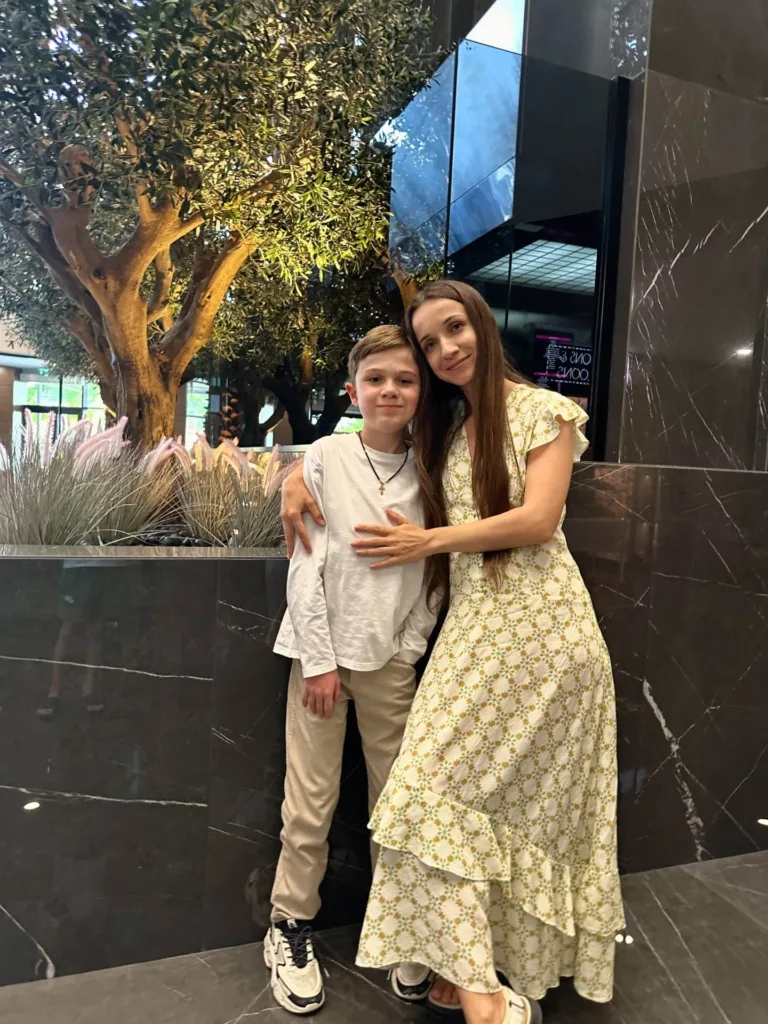 Жінка і хлопчик позують біля дерева в приміщенні