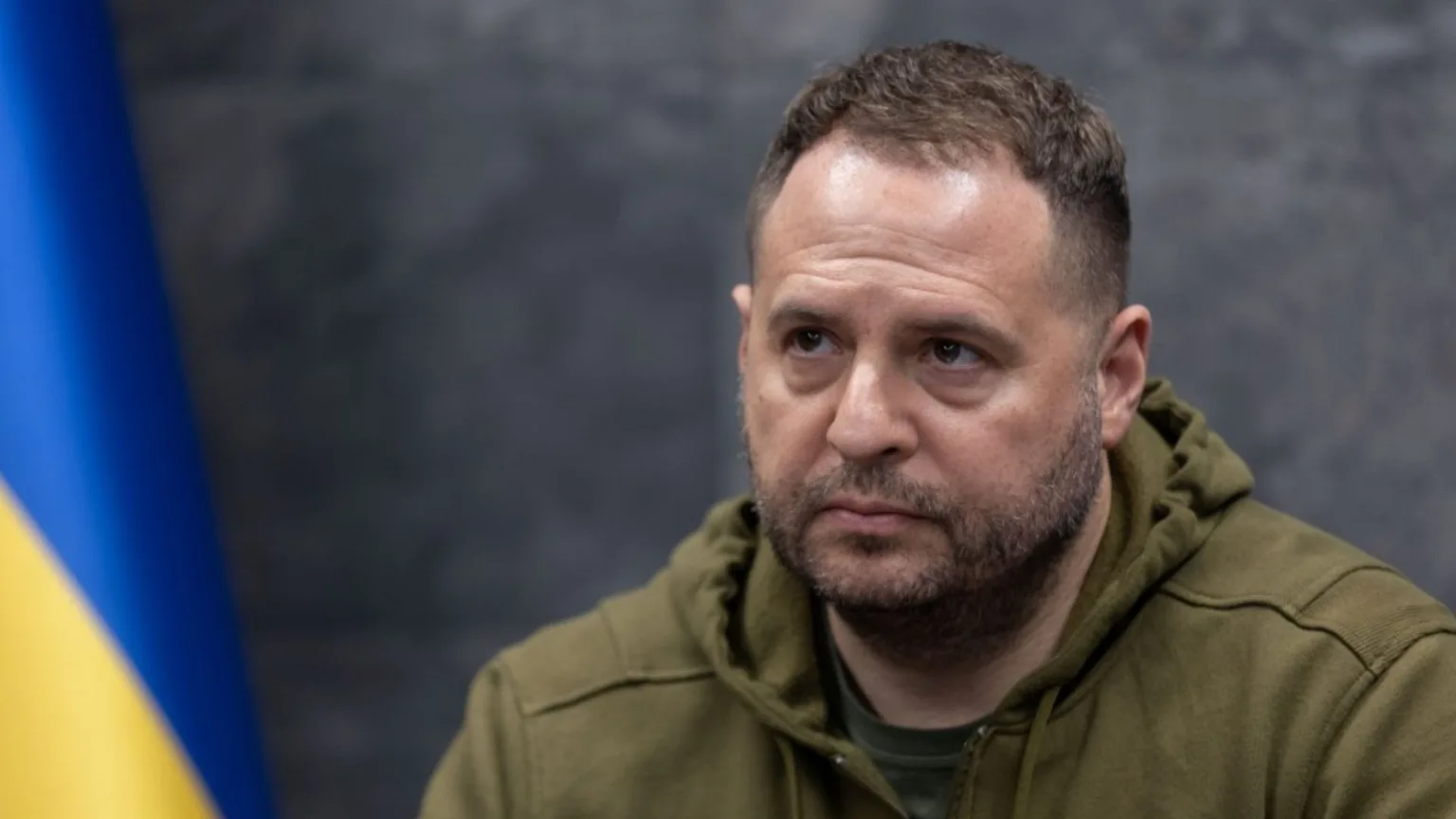 Чоловік у зеленому одязі перед прапором України