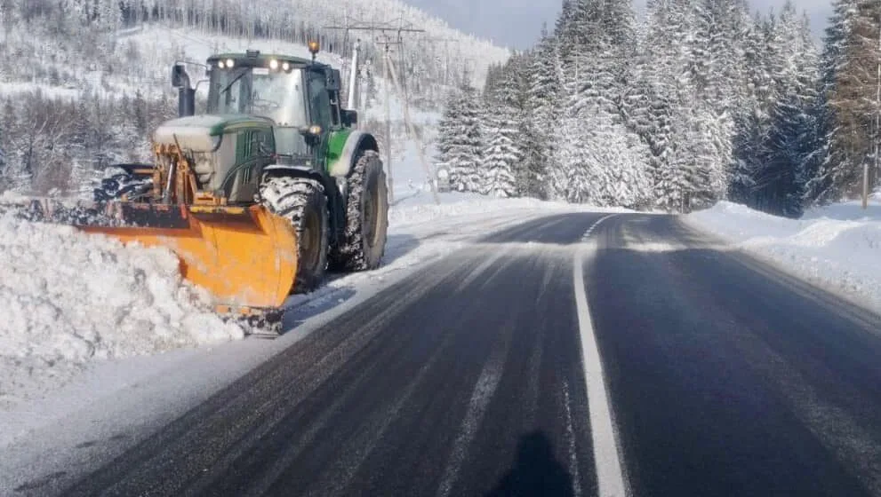 Трактор розчищає сніг на зимовій дорозі