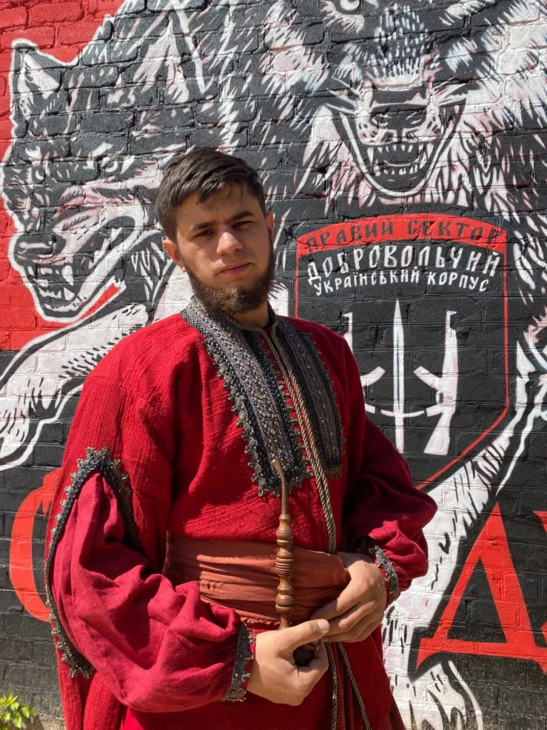 Чоловік у червоному вбранні перед графіті вовка