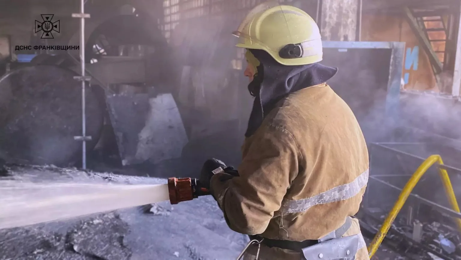 Пожежник гасить вогонь у промисловому приміщенні