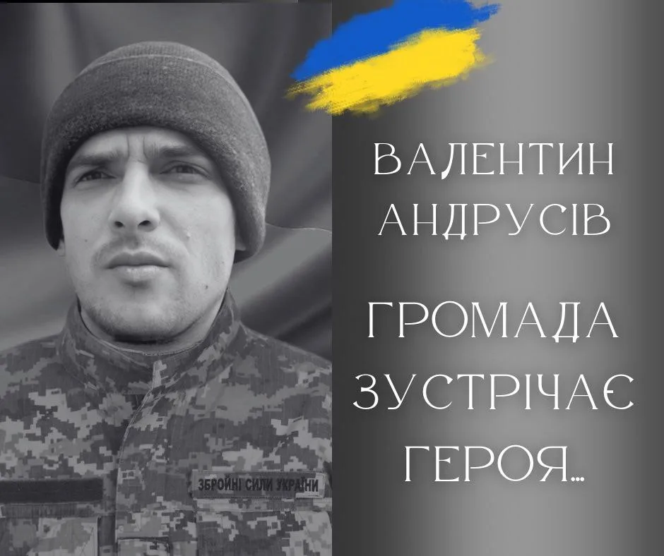 Український військовий у камуфляжі перед прапором України