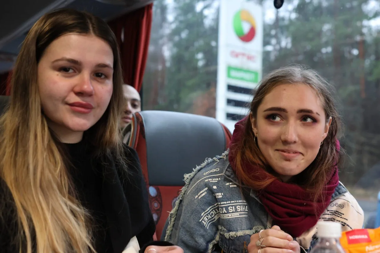 Дві дівчини сидять у автобусі, емоційно посміхаються.