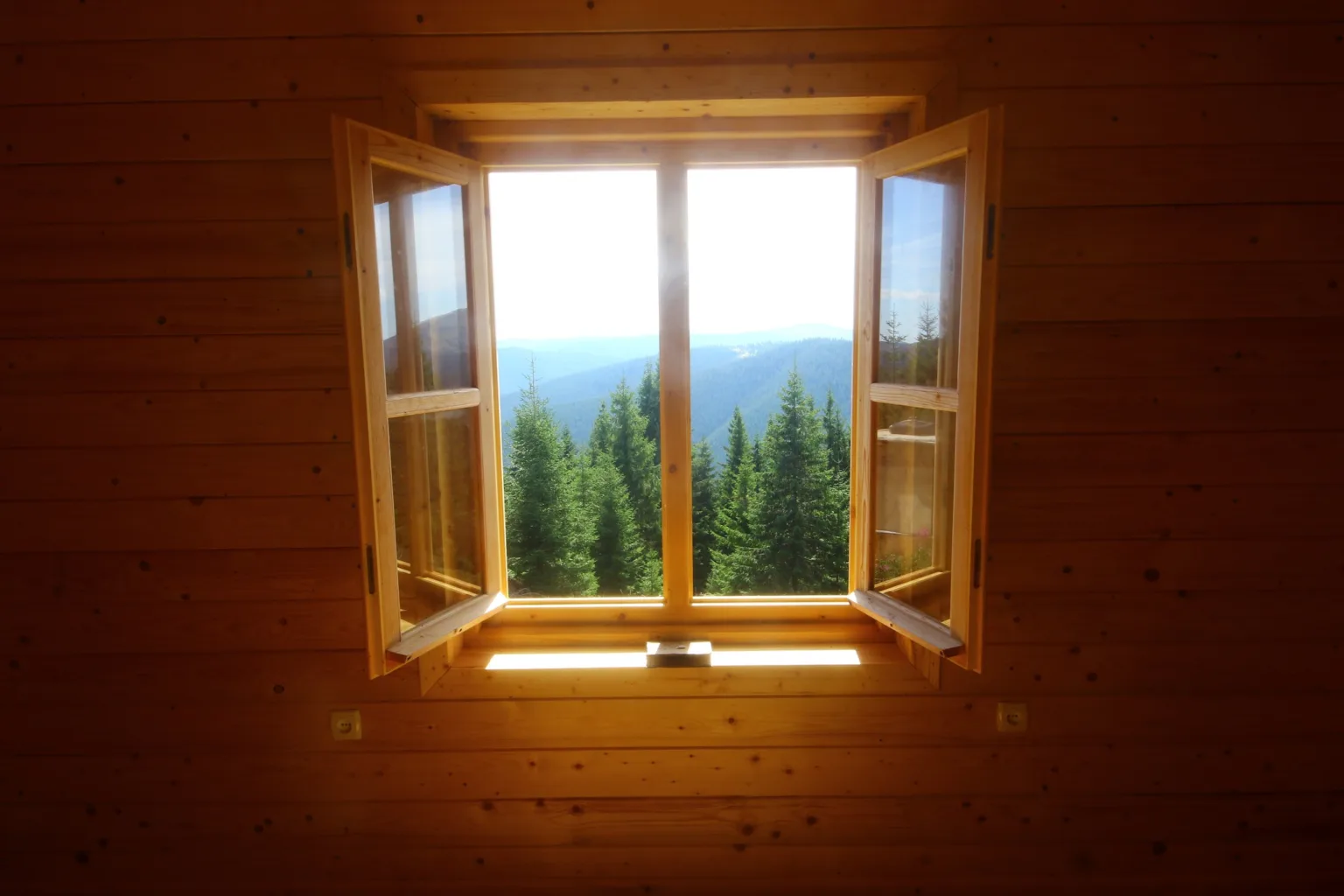 Відкрите вікно дерев’яного будинку з видом на гори