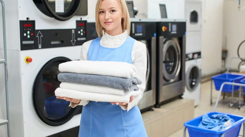 Працівниця пральні тримає складені рушники