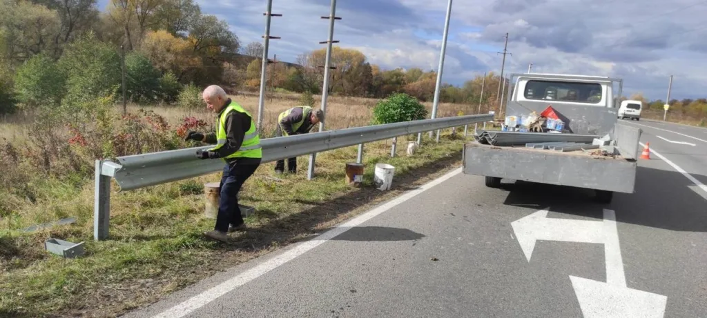 Робітники ремонтують відбійник на узбіччі дороги