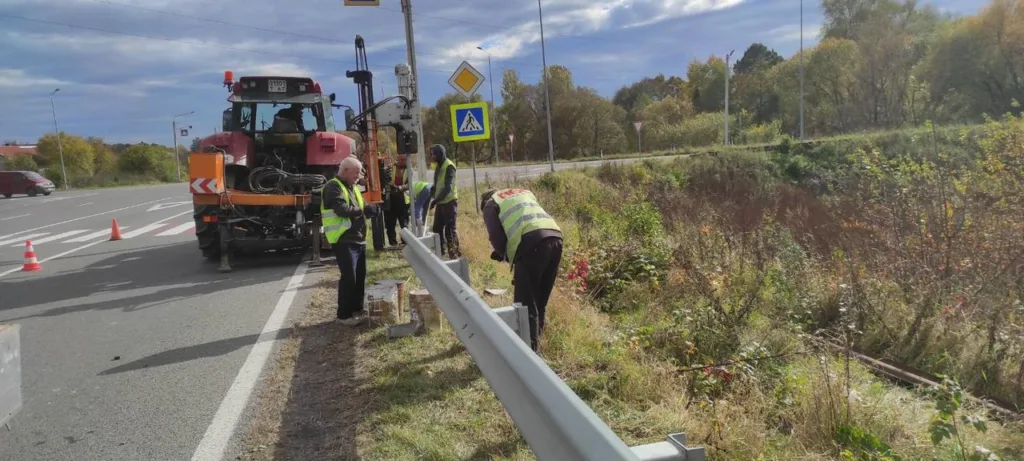 Робітники встановлюють відбійник на узбіччі дороги