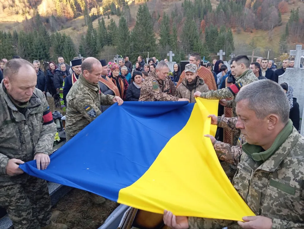 Військові тримають український прапор на церемонії поховання