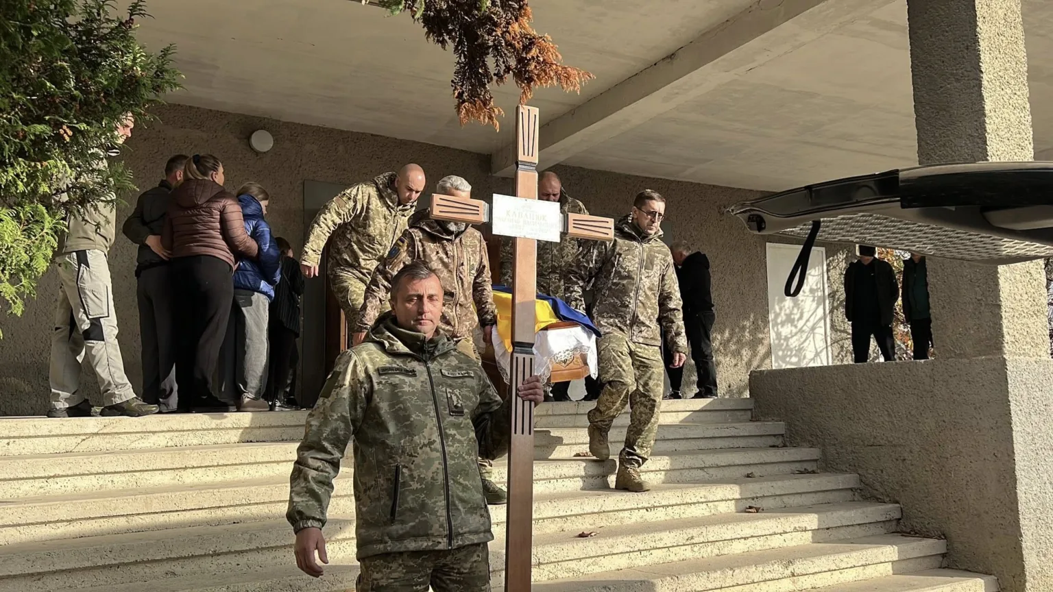 Військові несуть труну, накриту українським прапором