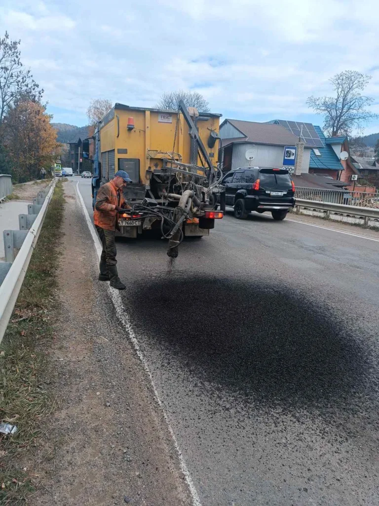 Робітник ремонтує асфальт на сільській дорозі
