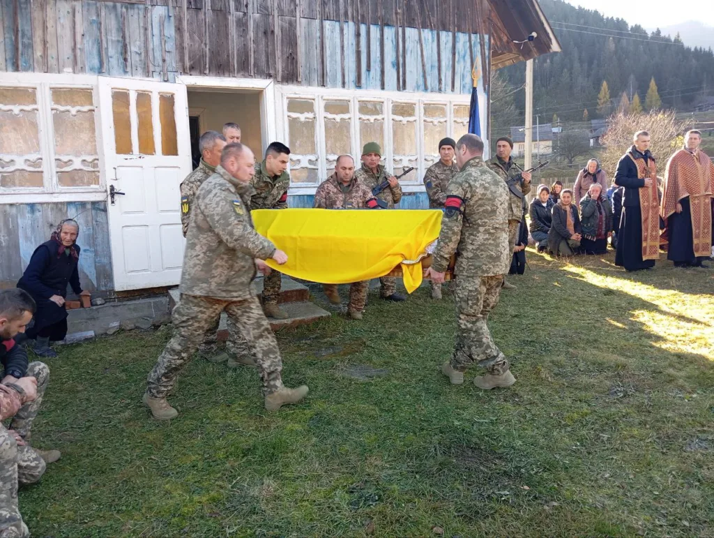 Військові несуть труну, накриту прапором України