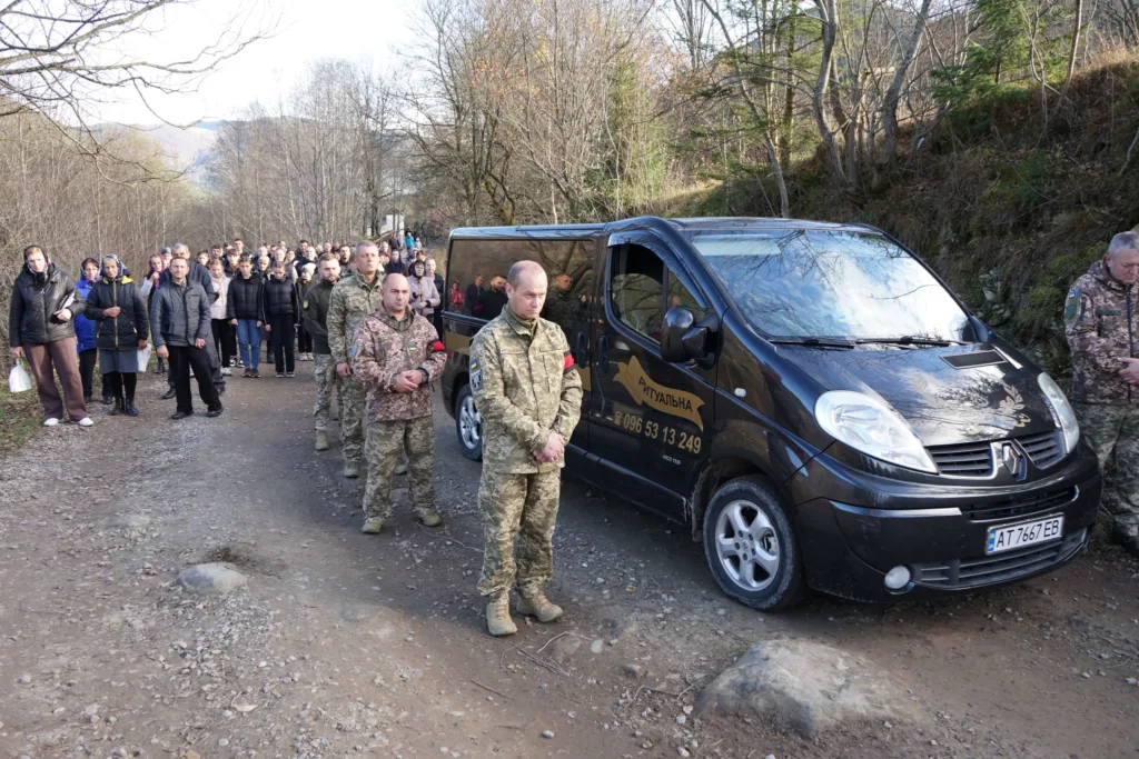 Похоронна процесія з військовими та людьми в селі