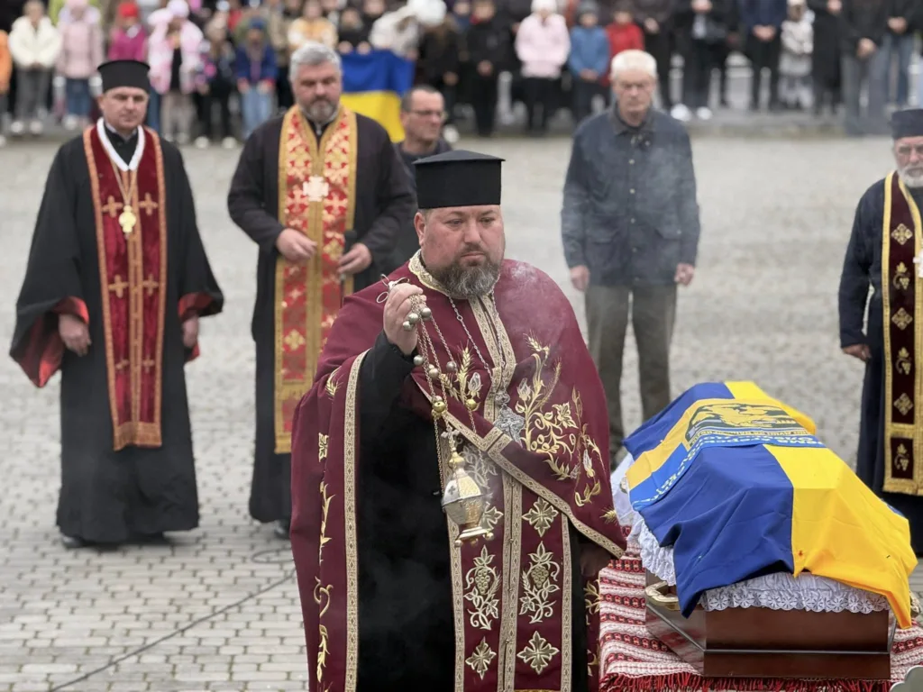 Священники проводять церемонію біля труни з прапором України