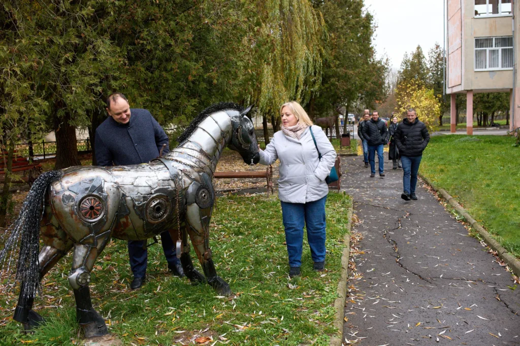 Люди оглядають металеву скульптуру коня в парку