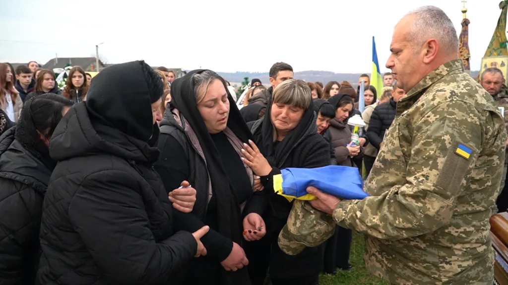 Військовий передає прапор родині загиблого героя