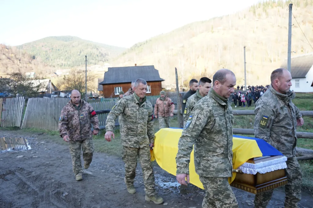 Військові несуть труну, покриту українським прапором