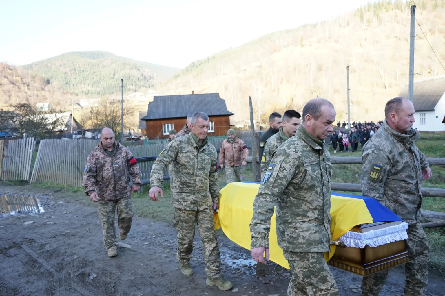 Військові несуть труну, покриту українським прапором