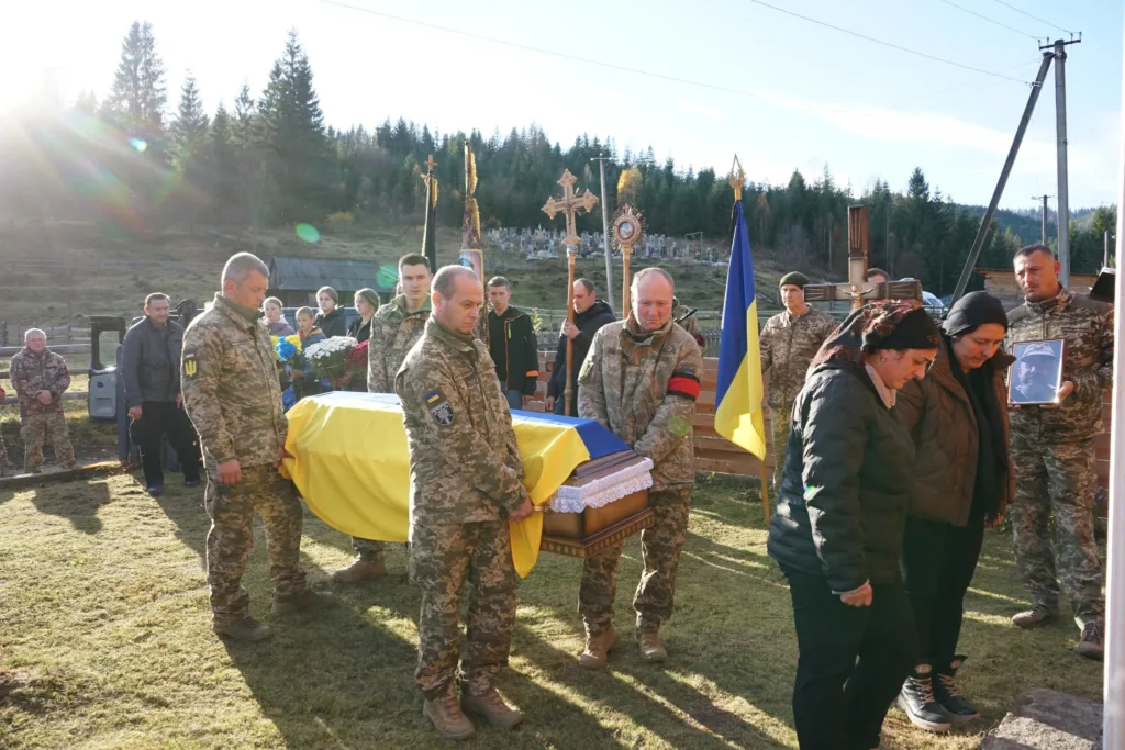 Військові несуть труну, накриту українським прапором