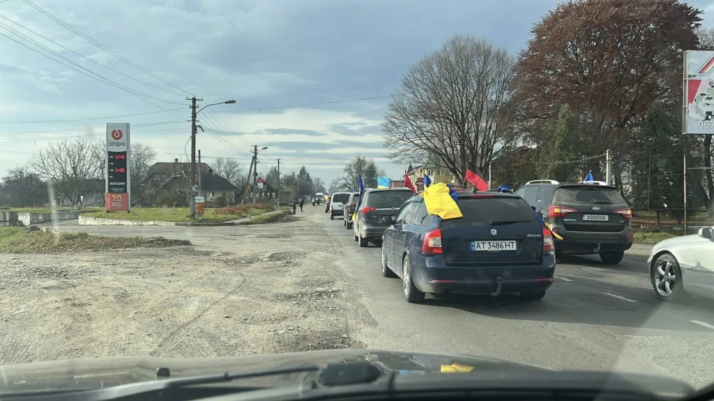 Автоколона з українськими прапорами на сільській дорозі