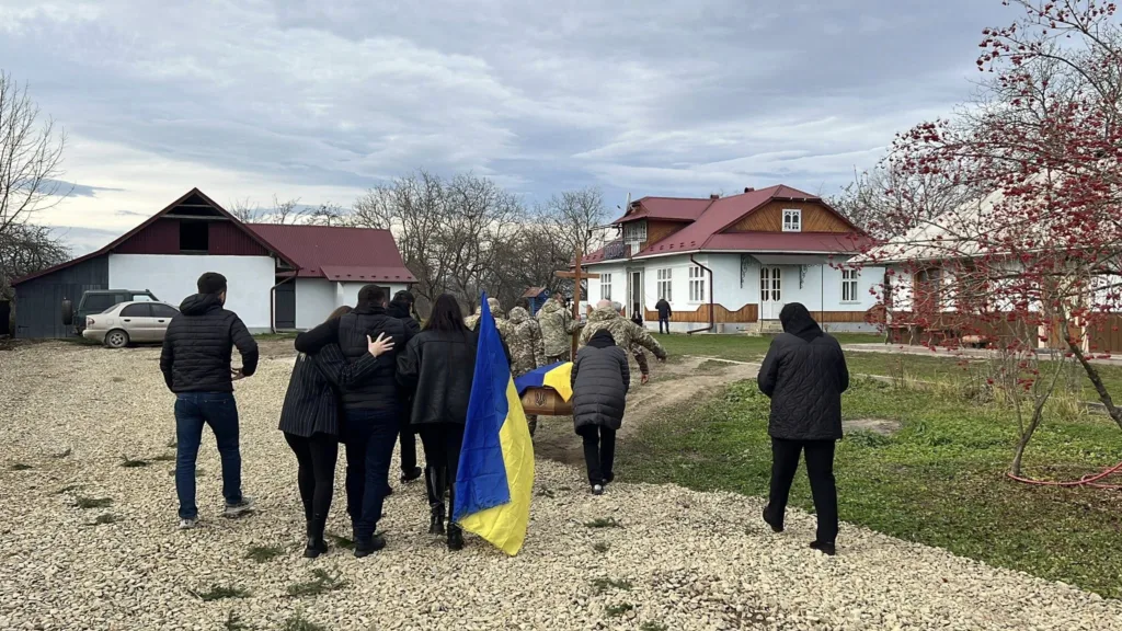 Похоронна процесія з українським прапором у селі