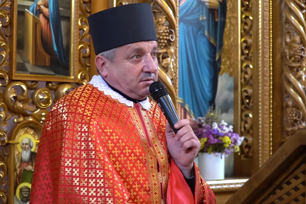 Священник говорить у мікрофон під час служби