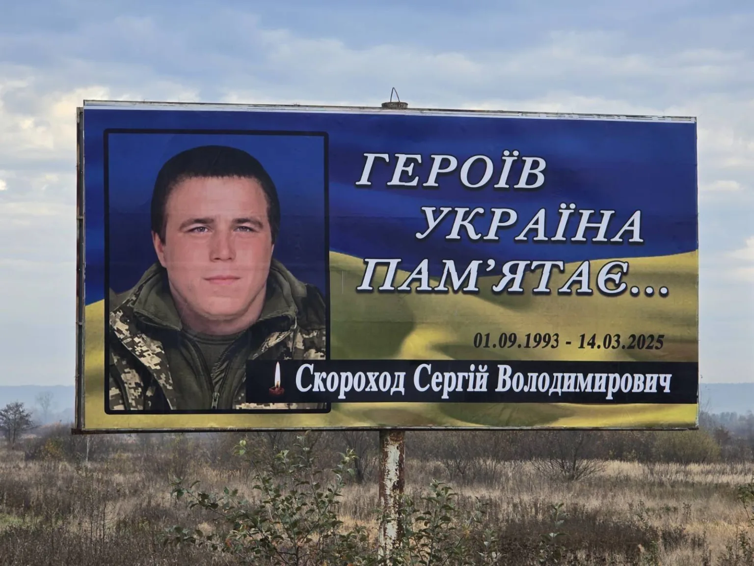 Пам'ятний білборд українського героя на тлі прапора