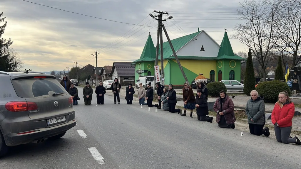 Люди на колінах уздовж дороги в українському селі