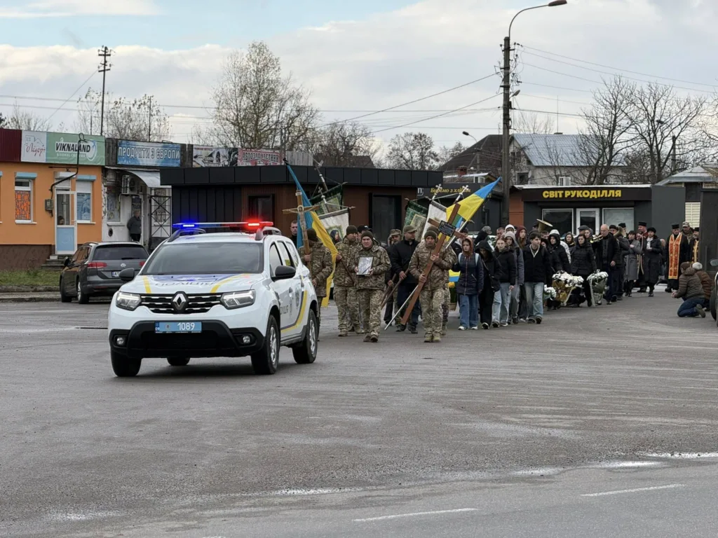 Процесія з військовими та поліцейським автомобілем на вулиці